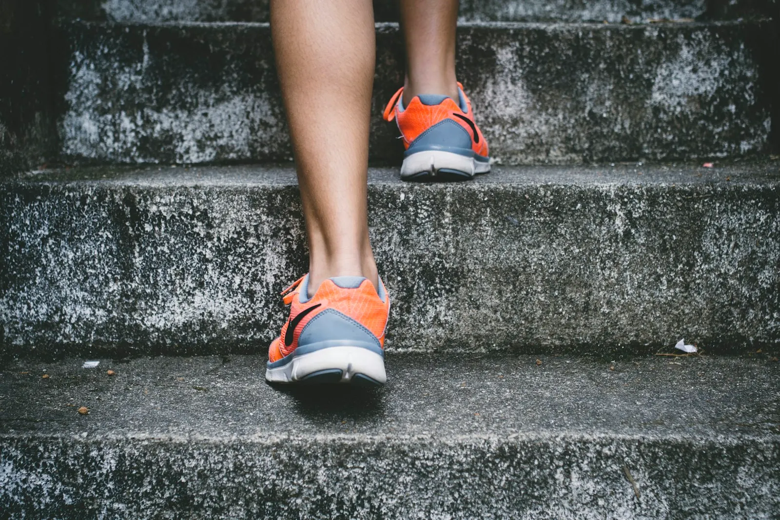 Runner in orange shoes moving up outdoor steps
